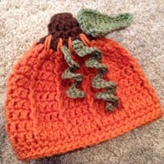 an orange crocheted bag sitting on top of a carpet next to a pair of shoes