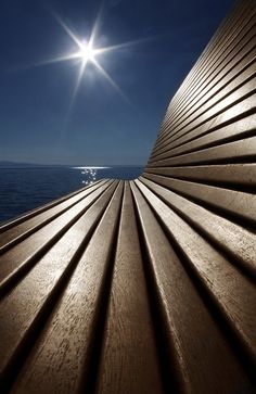 the sun shines brightly on top of a wooden structure by the water's edge