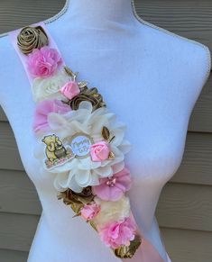 a white mannequin with pink flowers on it's neck and some gold accents