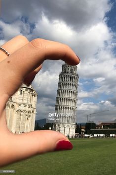 a woman's hand holding up the leaning tower of pisa, italy stock photo