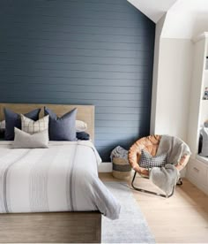 a bedroom with blue walls and white bedding in the corner, along with a chair