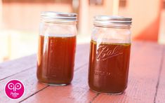 two jars filled with liquid sitting on top of a wooden table