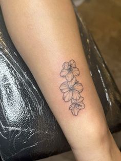 a woman's leg with a tattoo on it that has three flowers in the middle