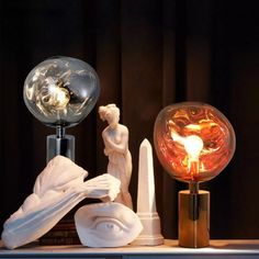 a table topped with two glass globes next to a statue and a light bulb