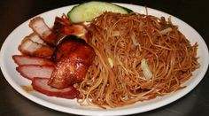 a white plate topped with meat and noodles