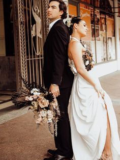 a man and woman standing next to each other in front of a building holding hands