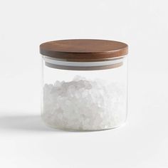 a glass jar filled with white rice on top of a wooden lid next to a brown lid