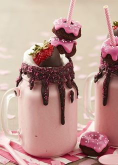 two cups with strawberries and chocolate covered in pink frosting, one is filled with whipped cream and the other has sprinkles