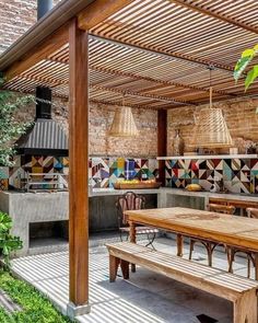 an outdoor kitchen and dining area with wooden table, benches and potted plants in the background