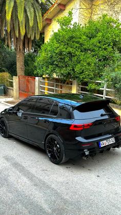 a black car parked in front of a palm tree