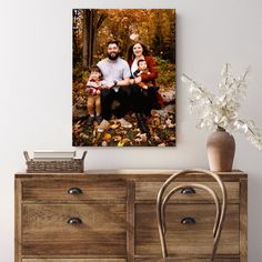 an image of a family sitting together in the woods on a fall day with leaves all around them