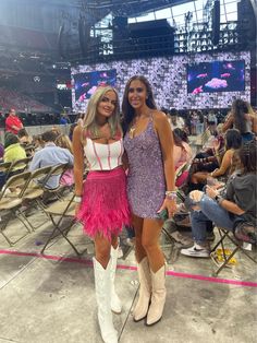 two beautiful women standing next to each other in front of a crowd at a sporting event