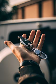 a hand holding a cell phone with a keychain on it's thumb