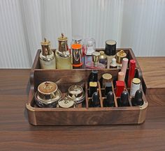 a wooden box filled with lots of different types of cosmetics and perfume bottles on top of a table