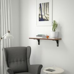 a gray chair sitting next to a white table with a potted plant on it