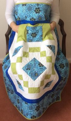 a woman sitting in a chair holding a quilt