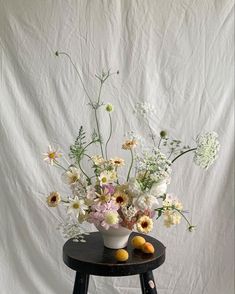 an arrangement of flowers in a vase on a stool