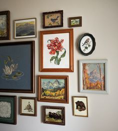 a wall with many framed pictures and paintings on it's side, including flowers