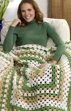 a woman sitting on a couch with a green and white blanket