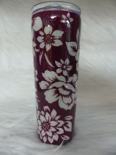 a purple and white flowered tumbler sitting on top of a fur covered floor