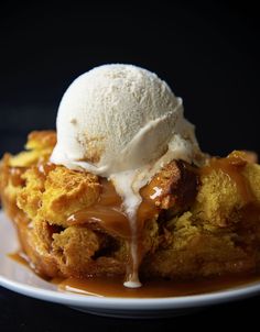 a dessert with ice cream and caramel sauce on a white plate in front of a black background