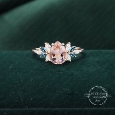 an engagement ring with pink sapphire and blue topazte stones on a green velvet surface