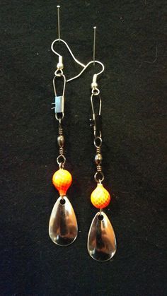 pair of earrings with orange and yellow bead hanging from silver earwires on black background