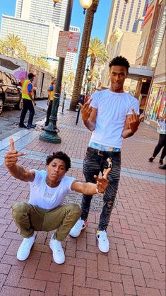 two young men posing for the camera on a city street