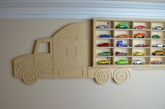 a wooden toy truck is next to a wall shelf with cars on it and shelves