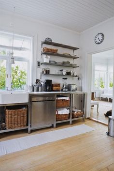 a kitchen with stainless steel appliances and open shelving on the wall next to a wooden floor