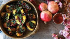 a bowl filled with food next to some apples and other fruit on top of a wooden table