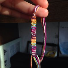 a hand holding a multicolored piece of string