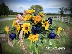 a bouquet of sunflowers and blue roses tied to a wooden fence in front of a field