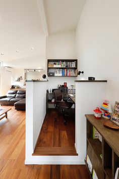 an office area with hard wood floors and white walls, along with bookshelves