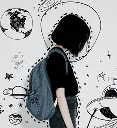 a woman standing in front of a wall with drawings on it and space around her