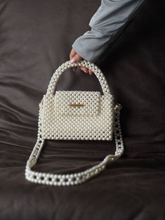 Handcrafted Beaded Pearl Bag - Elegance in Every Bead Unveil the epitome of timeless glamour with our exquisite Beaded Pearl Bag--a fusion of sophistication and craftsmanship that's perfect for the modern-day diva. Whether you're attending a wedding, a gala, or a stylish soirée, this beaded pearl bag is designed to elevate your outfit. It effortlessly transitions from day to night, making it a versatile accessory for every occasion. Despite its petite appearance, this bag is surprisingly spaciou White Evening Shoulder Bag With Detachable Handle, Elegant Cream Square Shoulder Bag, Elegant Shoulder Bag With Pearl Handle, White Rectangular Shoulder Bag With Pearl Handle, White Shoulder Bag With Pearl Handle, Cream Rectangular Shoulder Bag With Pearl Handle, Cream Top Handle Bag With Pearl Handle, Cream Top Handle Bag With Pearl Detail, White Square Shoulder Bag For Party