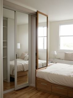 a bedroom with a bed, mirrored closet doors and wooden floors in front of a window