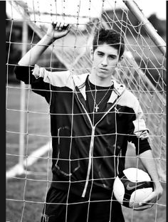 a young man holding a soccer ball in front of a goalie's net