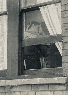 an old photo of two people in a window