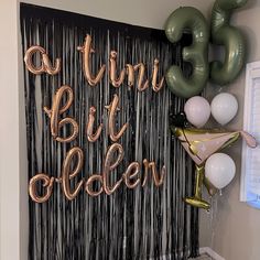 balloons and streamers are hanging on the wall in front of a party backdrop that says,'a thin bit older '