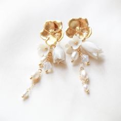 Make a statement on your special day with our gorgeous CALLIE Freshwater Pearl Floral Earrings! Perfect for any modern bride, they combine golden tones with glimmering pearl accents to create an exquisite flowery design. A must-have accessory to complete your look! - PLEASE ALLOW APPROX 10 BUSINESS DAYS FOR COMPLETION BEFORE SHIPPING. - Handcrafted with genuine freshwater pearls and Austrian crystals- Created in my studio in PA- White opal crystals- Freshwater pearls- Polymer clay flowers - Yell Feminine Gold Jewelry With 3d Flowers, Delicate Flower-shaped Earrings With Pearl Charm, Delicate White Bridal Earrings With Pearl Charm, Gold Flower Chandelier Earrings Elegant Style, Gold Feminine Flower Earrings With 3d Flowers, Gold Flower-shaped Elegant Chandelier Earrings, Wedding Flower Earrings With Pearl Charm, Elegant Gold Flower Chandelier Earrings, White Bridal Earrings For Celebration With Elegant Design