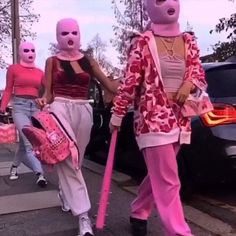 three people in pink and white costumes walking down the street with one holding a pink handbag