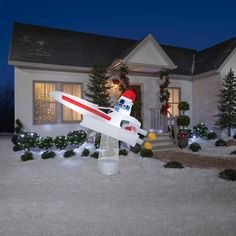 a toy airplane sitting in front of a house at night with christmas decorations around it