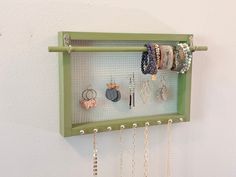 a wall mounted jewelry rack with several pairs of earrings hanging from it's sides