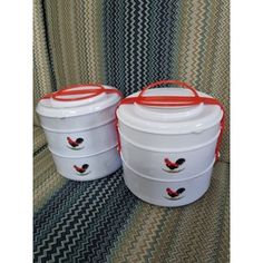 two white buckets with red handles sitting next to each other