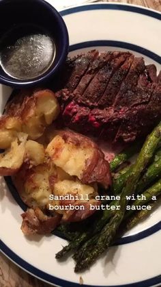 a plate with steak, potatoes and asparagus on it