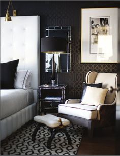 a white bed sitting next to a chair in a room with black and white walls