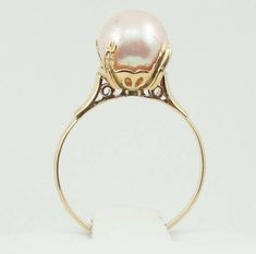 "This vintage 18K yellow gold ring features a blushing pink colored pearl held by four curving prongs above a gorgeous ornate gallery. Marked K18. Certain to be a favorite in your personal jewelry collection. FREE SHIPPING! Details: 18K Yellow Gold: (as shown in picture) Natural Pink Cultured Pearl 8 mm Ring Size: 5 3/4 Total Weight: 2.6 grams FREE domestic shipping by USPS Priority Mail Signature Confirmation and includes insurance. If the item is to be shipped internationally Etsy will auto-ca Pink Pear-shaped Ring For Formal Occasions, Pear Shaped Pink Ring For Formal Occasions, Pink Pear-shaped Formal Rings, Formal Pink Pear-shaped Rings, Pink 14k Stamped Wedding Jewelry, Pink 14k Stamped Jewelry For Wedding, Elegant Pink Cabochon Rings, Pink Pearl Ring For Wedding, Elegant Pink Pearl Round Ring