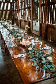 a long wooden table topped with flowers and greenery