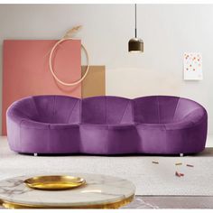 a purple couch sitting on top of a white floor next to a table and lamp